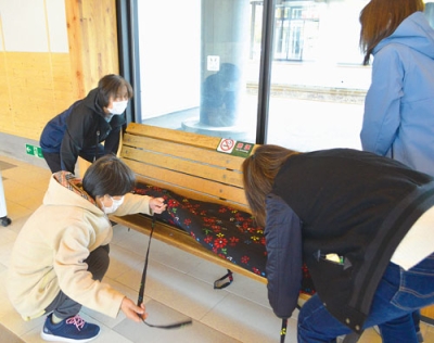 写真：ベンチに座布団を敷く会員たち