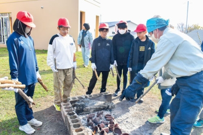 写真：まきを手にオリジナル縄文土器の焼き上がりを待つ虻田小児童ら