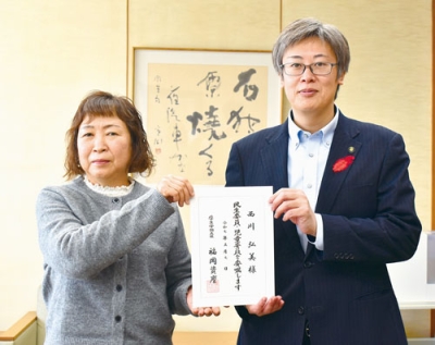 写真：民生委員児童委員の委嘱状を受けた西川さん（左）