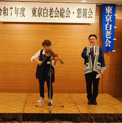 写真：あいさつする大塩町長（右）。左は白老町観光大使のバイオリニスト・牧千恵子さん（提供写真）