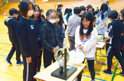 写真：うちわで風車を動かし、電気を起こす実験に臨む児童ら