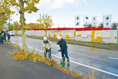 写真:新庁舎建設現場沿いで落ち葉を拾い集める参加者ら