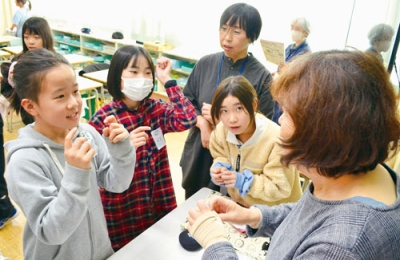 写真：宮武さん（右）の指導を受けながら手話を練習する児童たち