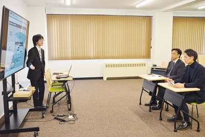 写真：望月代表取締役（右から２人目）らに業務改善案をプレゼンする赤坂さん