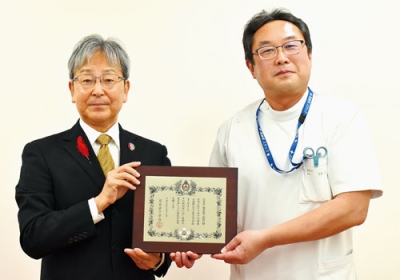写真:長年の献血協力が認められ、銀色有功章の伝達を受ける目良院長(右)