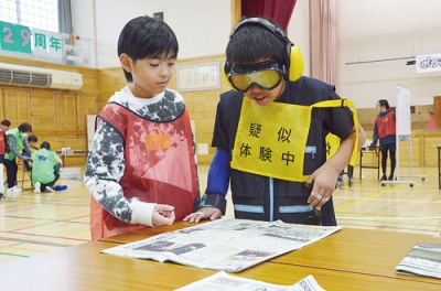 写真:ゴーグルをかけ新聞を読む児童