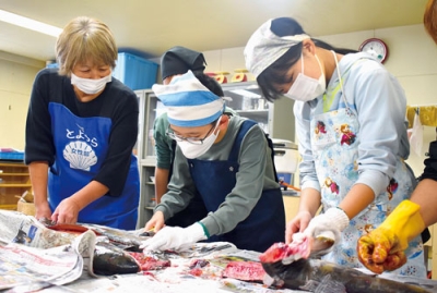 写真：真剣なまなざしでサケに包丁を入れる児童