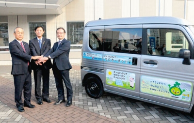 写真：カーシェアリングする車両の横で握手する（左から）中田会頭、青山市長、牧野局長
