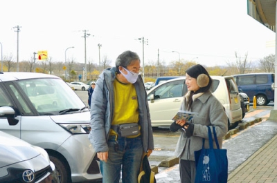 写真：買い物客に啓発物を渡す市職員