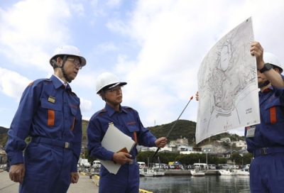 写真：大分市佐賀関の火災現場を訪れ、被災状況の説明を受ける大分県の佐藤樹一郎知事（左）＝２０日午前１１時２分