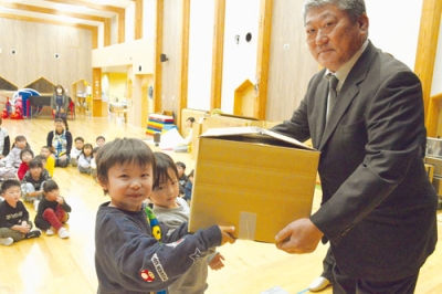 写真:川浪会長(右)からタオルを受け取る子どもたち