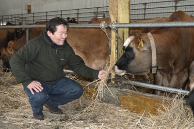 写真:牛の世話をする「ファームズ千代田」のアブガンドロージン・アバラゼデ社長=美瑛町