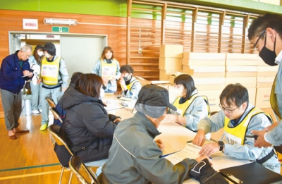 写真：避難者カードに必要事項を記入する訓練参加者ら＝虻田小学校