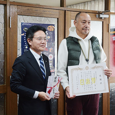写真：町に現金１００万円を寄付した髙田代表取締役（右）と大塩町長