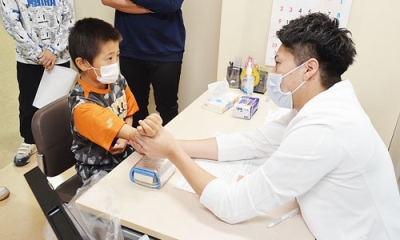 写真：球児の肘をチェックするメディカルチームの医師（右）