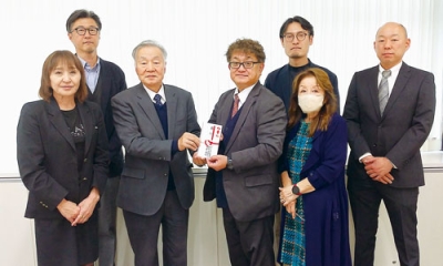 写真：寄付を贈る亀井道央ブロック長（中央）と、善意を受け取る菅野理事長（左から３人目）