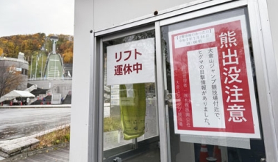 写真：大倉山ジャンプ競技場（左奥）の近くに掲示された「熊出没注意」のポスター＝１１月、札幌市