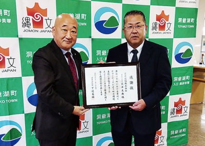 写真：感謝状を手にする三國常務取締役（右）