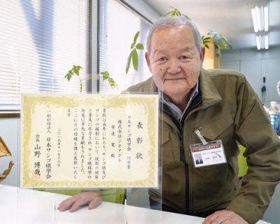 写真:地質調査会社「ジオアクト」の安達寛社長。左は日本サンゴ礁学会から贈られた功労賞の表彰状=北見市