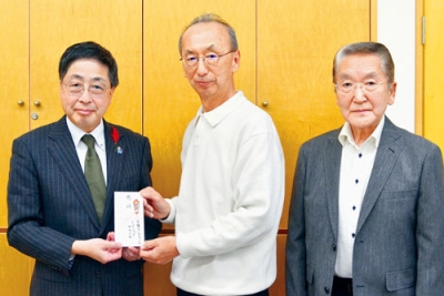 写真：髙木事務局長（左）に善意を手渡す柴原さん（中央）、小林さん