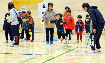 写真：体力テストで立ち幅跳びに挑む子どもたち