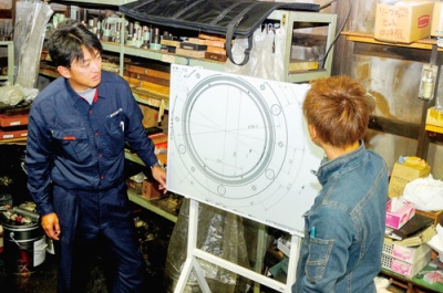 写真:電子ホワイドボードを使って図面を確認する寺本代表(左)