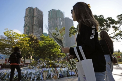 写真：火災があった高層住宅群近くに花を持って訪れた人たち＝２日、香港（共同）