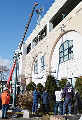 写真：クレーンでツリー型のイルミネーションを設置する関係者ら