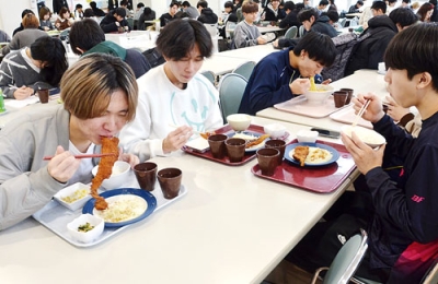 写真:スケソウダラのフライを味わう室蘭工業大の学生