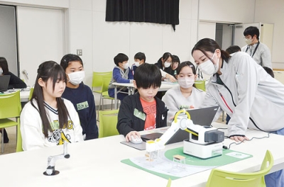 写真：プログラミングしたロボットのアームを動かす児童ら