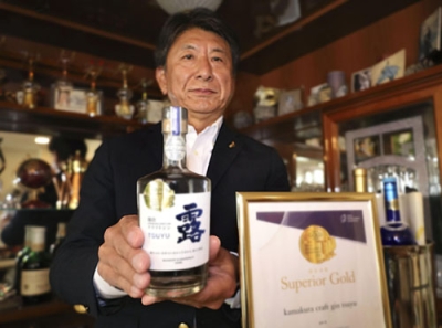 写真：「鎌倉クラフトジン露」を手にする秋山栄二さん＝１１月、神奈川県逗子市