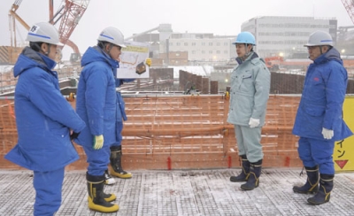 写真：北電泊原発の防潮堤工事現場を視察する鈴木直道知事（右から２人目）。右端は北電の斎藤晋社長＝４日午後（北電提供）