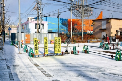 写真：陥没事故から１カ月がたった東町の市道。陥没地点はフェンスで保護され、手前の交差点は通行止めが続いている＝４日