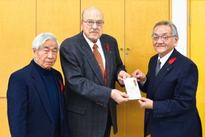 写真：ライヤ・フランシス主任司祭（中央）と運営委員長の松岡健一さん（左）から目録を受け取る國枝信会長