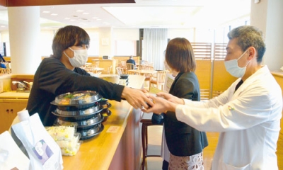 写真：ランチタイムにマルクマの弁当を購入する病院関係者（右）