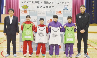 写真:折茂社長(右端)と篠原社長(左端)からビブスを受け取る子どもたち