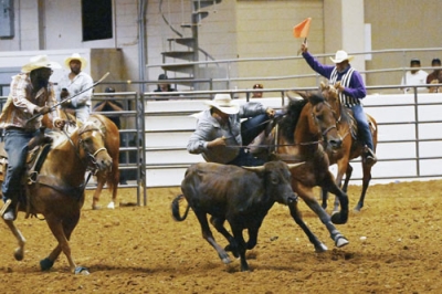 写真：７月、米テキサス州ダラスのロデオ大会で、馬に乗って走りながら子牛に飛び移る「スティール・レスリング」に出場した男性選手（共同）