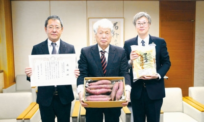 写真：組合員が丹精し育てたサツマイモを手にする佐藤組合長（中央）