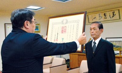 写真:小笠原市長から勲記を受け取る髙橋さん(右)