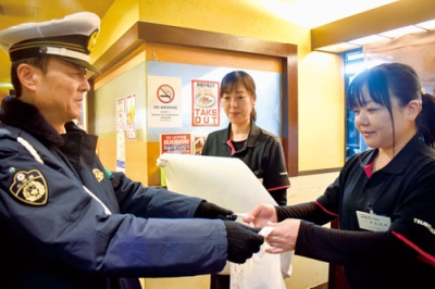 写真：店員に啓発物を配り、飲酒運転根絶への協力を求める渡部署長（左）