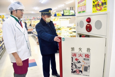 写真：店内の防火設備を目視で確認する消防職員（右）