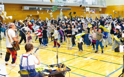 写真：「ひのき屋」の演奏に合わせ、ハンカチを投げて盛り上がる児童たち