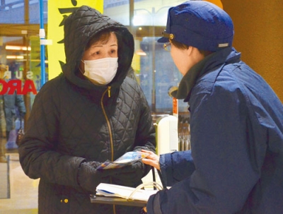 写真：来店客に啓発品を手渡し、交通安全を呼びかける室蘭署員
