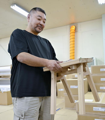 写真：商品のいすを手にする「石巻工房」の千葉隆博さん＝２０２５年１０月、宮城県石巻市