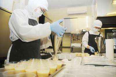 写真：手作業でプリンを容器に詰める従業員