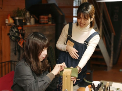 写真：革小物教室「Ｂｏｕｖａｒｄｉａ　Ｌｅａｔｈｅｒ　Ｗｏｒｋｓ」で参加者を指導するあなだちはるさん（右）＝大津市