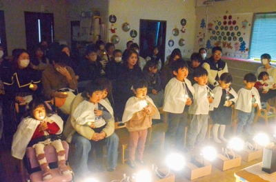 写真：発光ダイオードのろうそくをもって礼拝する子どもたち