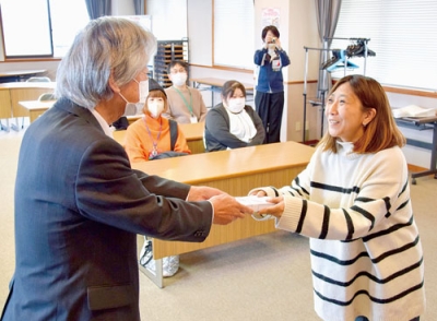 写真：長谷川会長（左）から見舞金を受け取る出席者