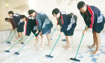 写真：床のタイルを丁寧に磨く従業員ら