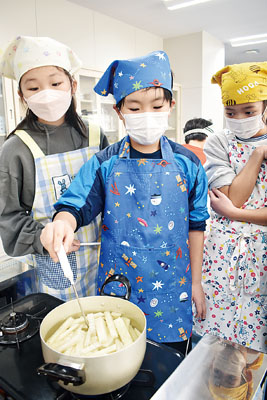 写真：温度計で適温を保ち、ビートから糖分を抽出する児童たち